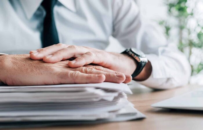 Insurance agent with stack of policy contracts on office desk