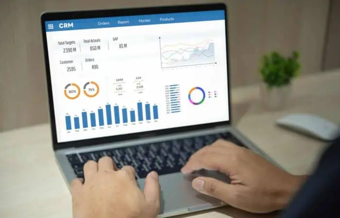 Man using computer laptop software with graphs and charts showing sales data. CRM Customer