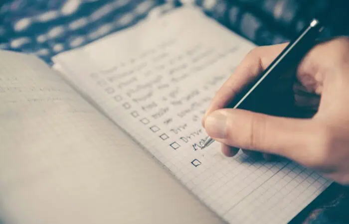 person writing bucket list on book